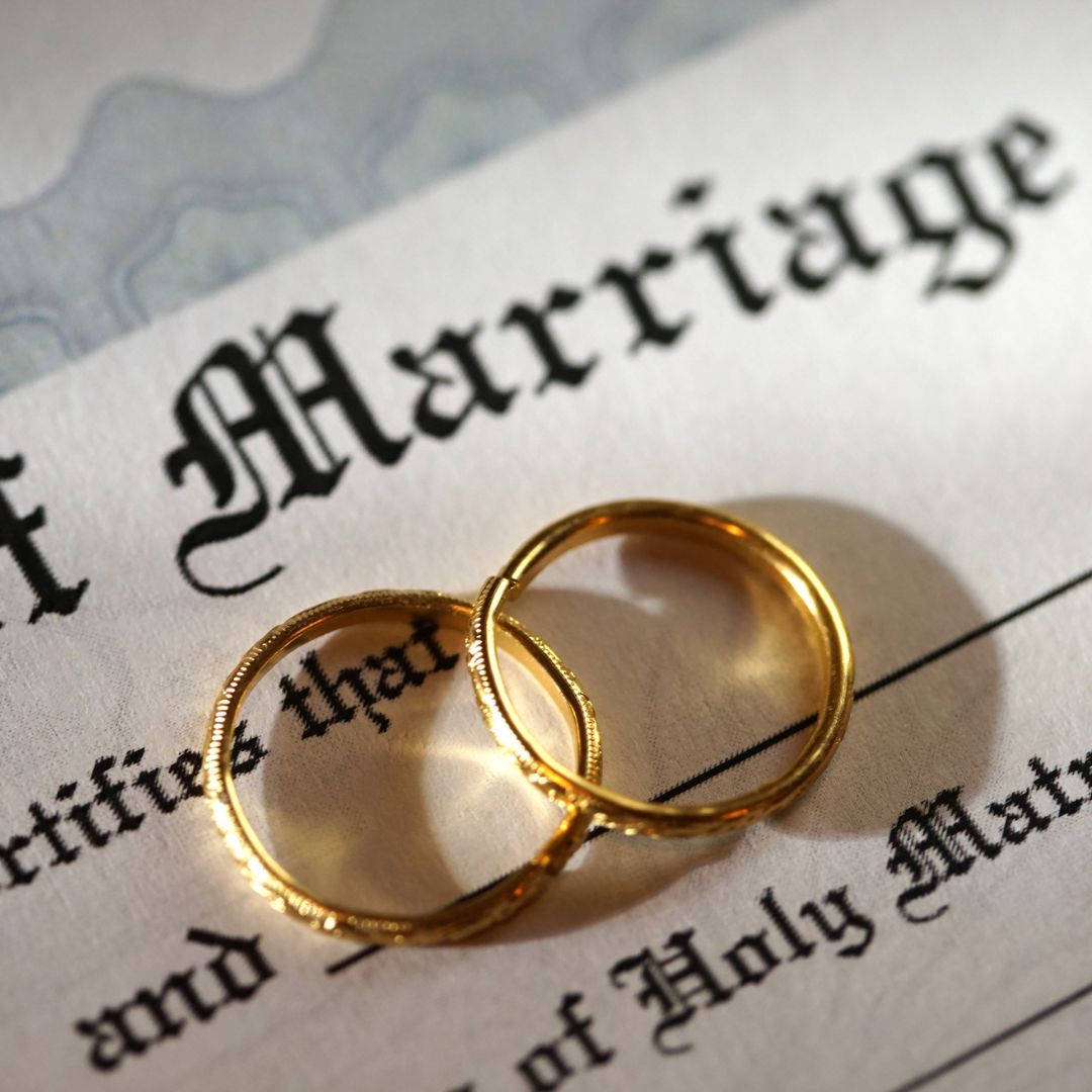 wedding rings sitting on a marriage certificate